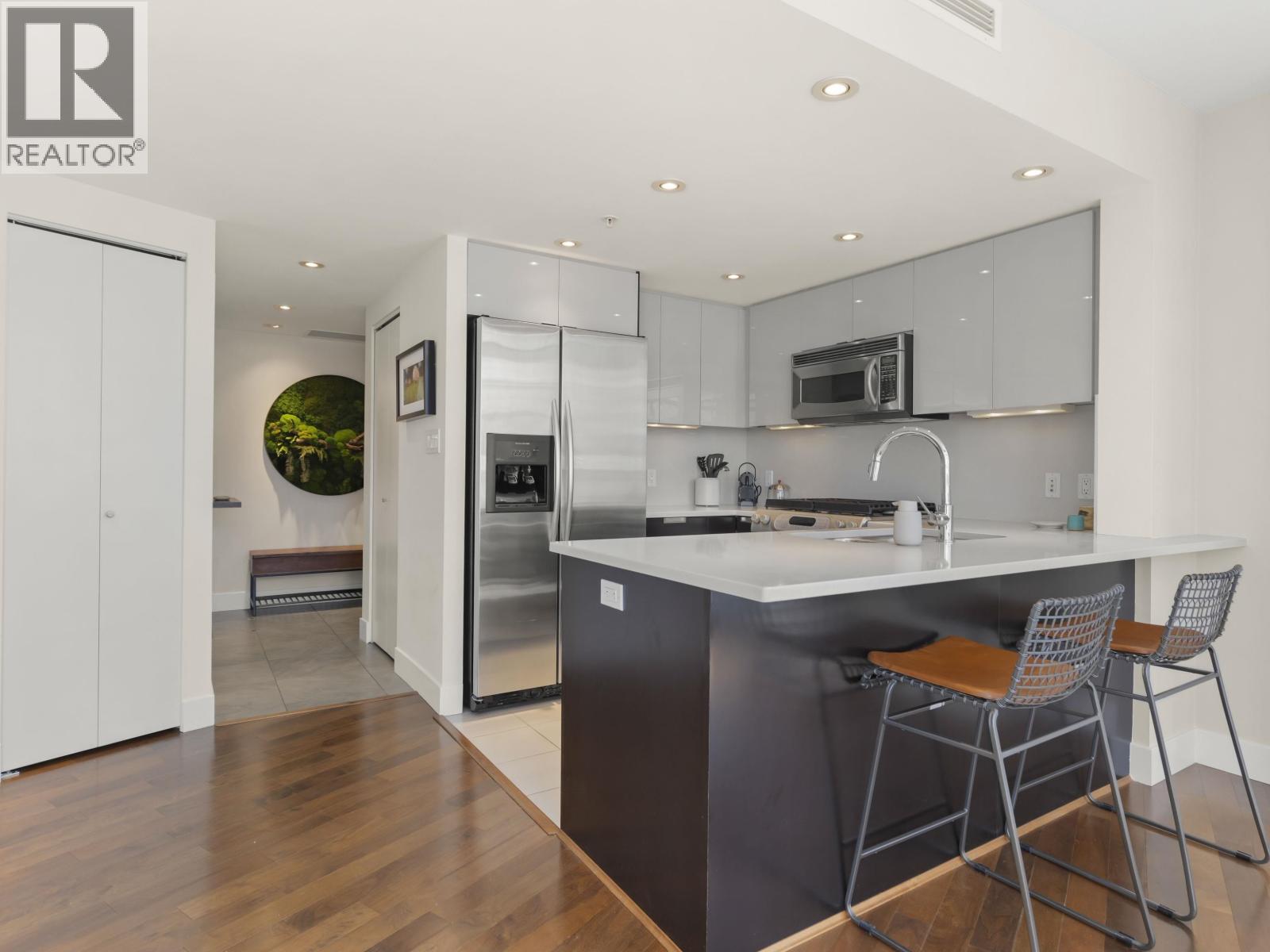 A modern kitchen with a bar stool and a fridge.