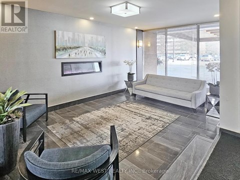A living room with a grey couch and a rug.