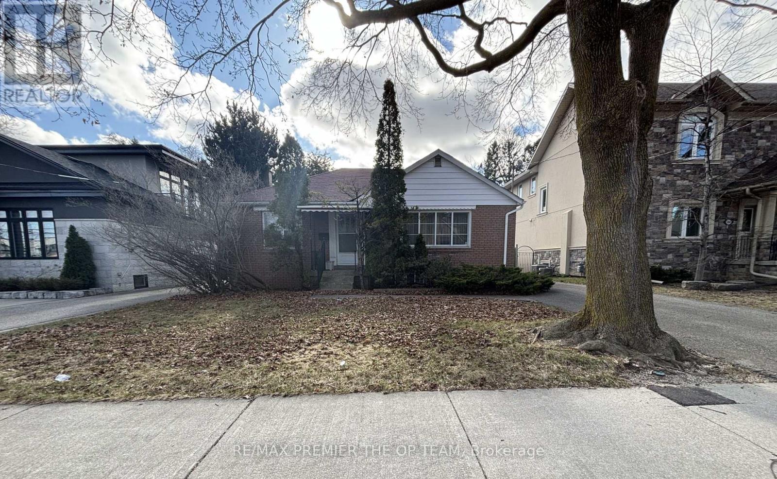 A tree stands in front of a house with a sign that says RE/MAX Premier The Opryland.