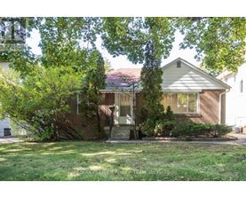 A house with a front yard and trees in the background.