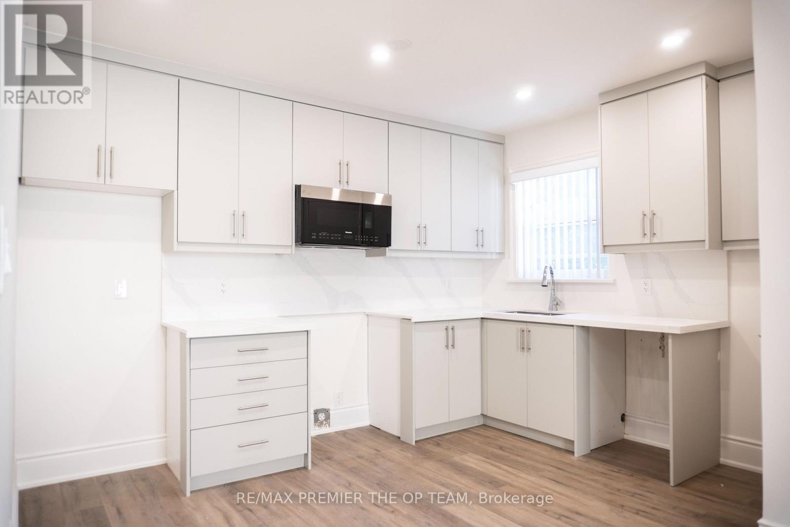 A kitchen with white cabinets and a microwave above the counter.