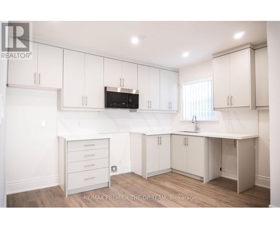A kitchen with white cabinets and a microwave above the counter.