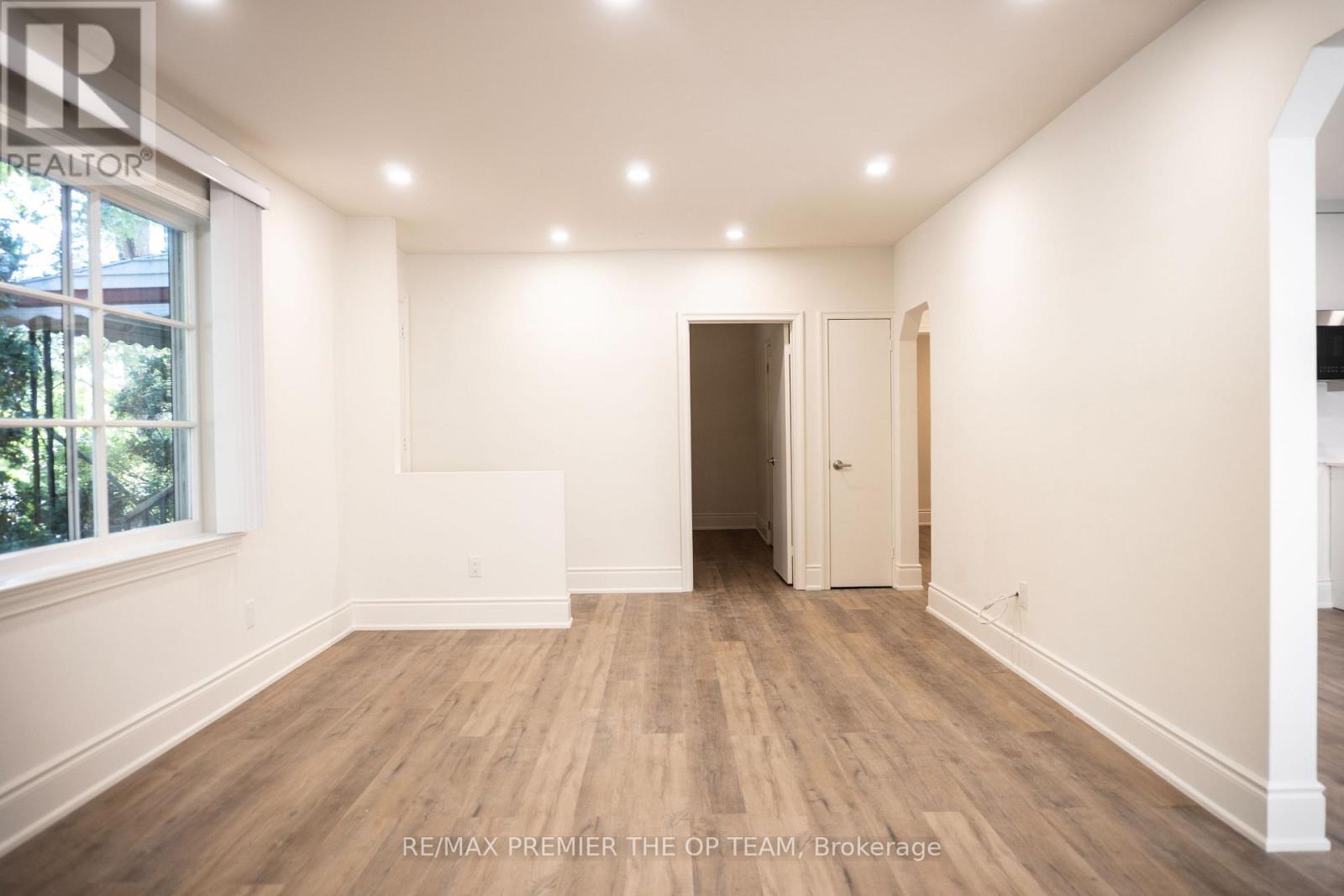 A spacious room with wooden flooring and white walls, ready for renovation.
