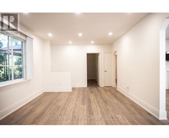 A spacious room with wooden flooring and white walls, ready for renovation.