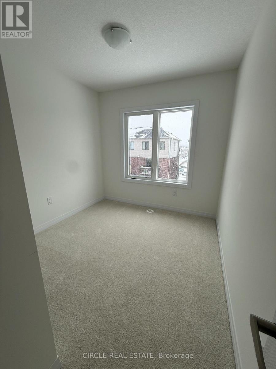 A bedroom with a carpeted floor and a window showing a view of a house.