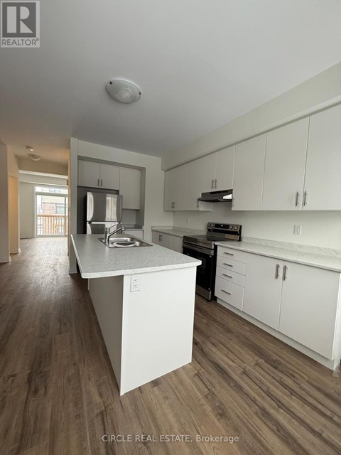 A kitchen with white cabinets and a wooden floor.