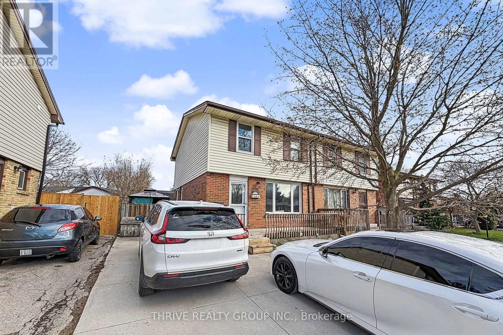A white car is parked in front of a house with a tree in the front yard.