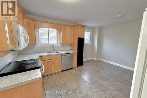 A kitchen with wooden cabinets and a black dishwasher.