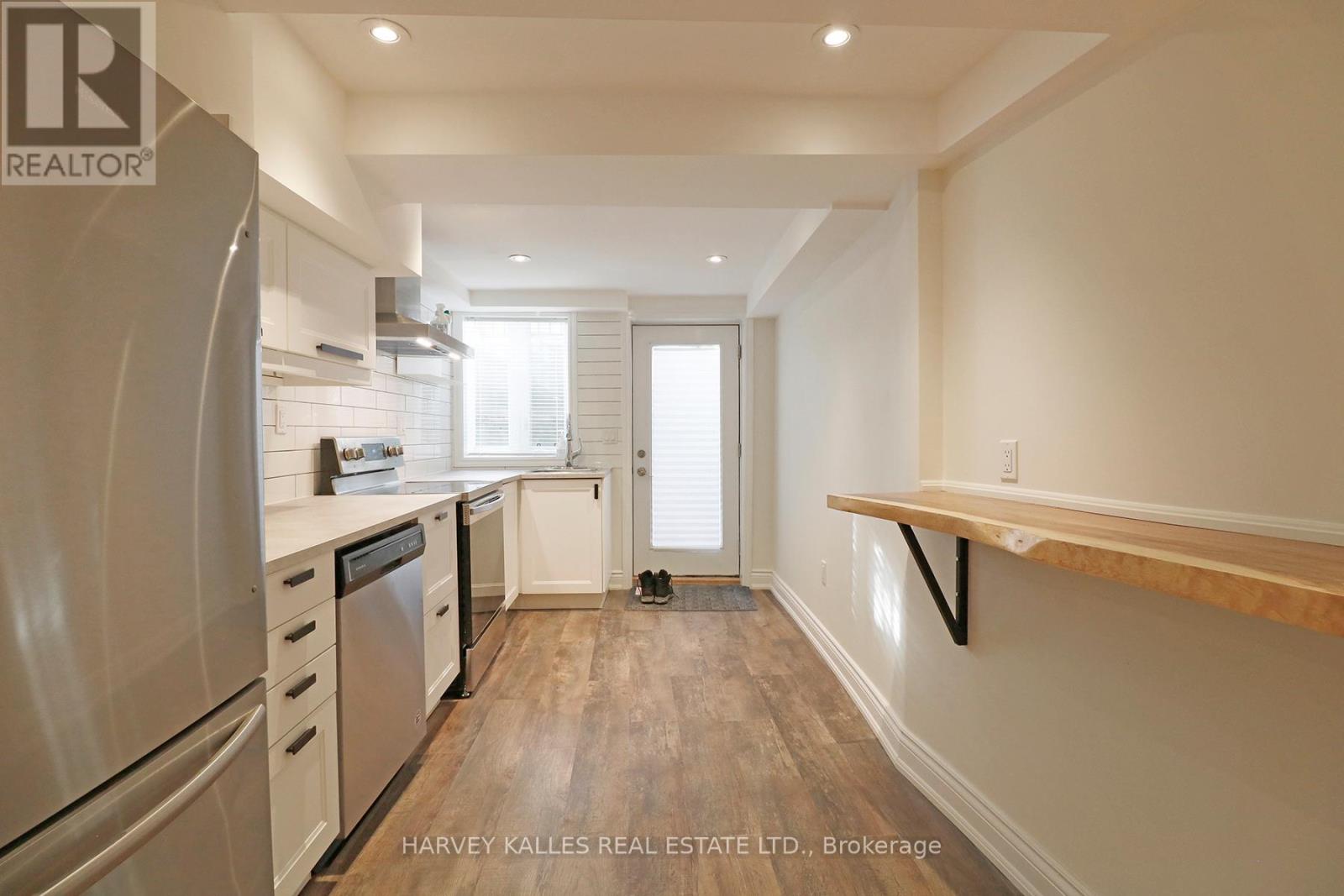 A kitchen with a refrigerator, oven, and sink.