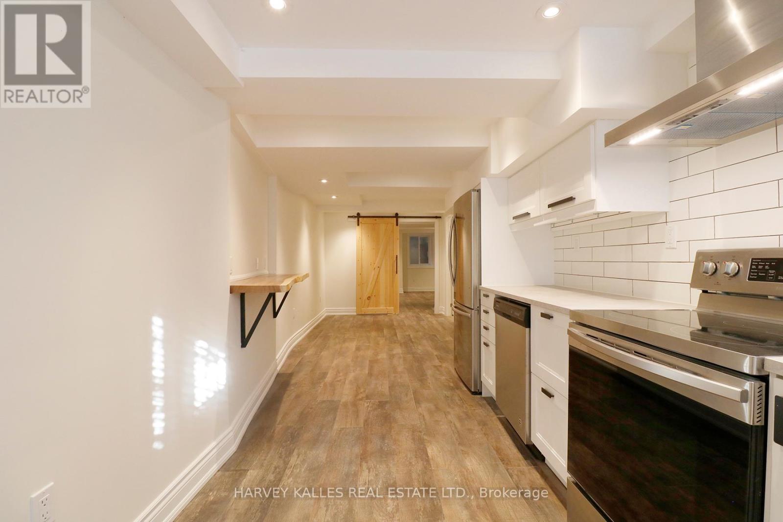 A kitchen with white cabinets and a wooden floor.