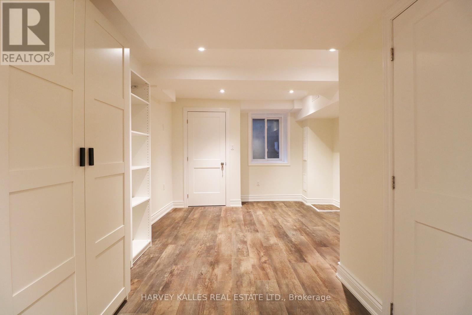 A spacious room with wooden flooring and white walls.