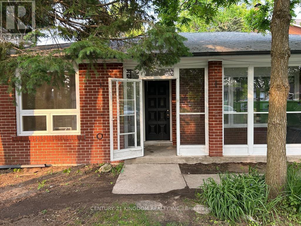 A red brick house with a white door and a tree in front.