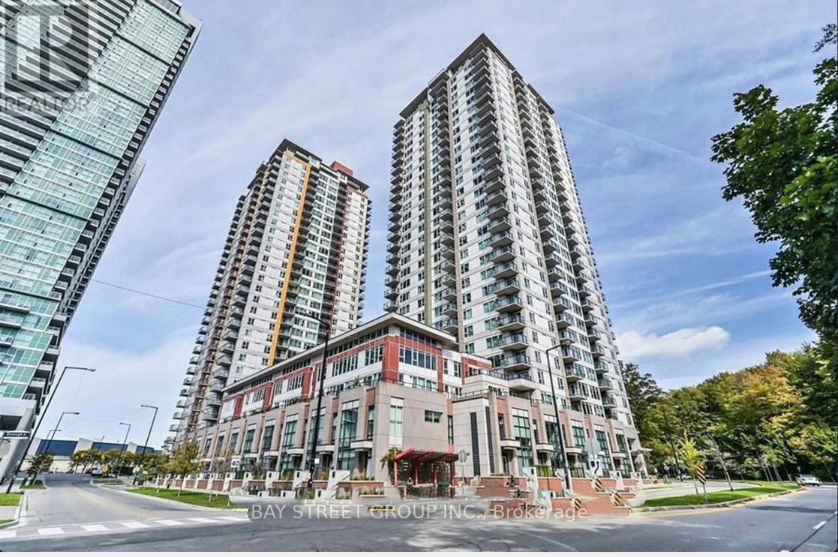 Two high-rise buildings are situated in front of a tree-lined street.