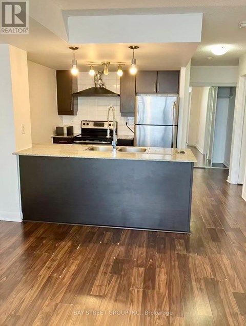 A kitchen with a black counter top and wooden floors.