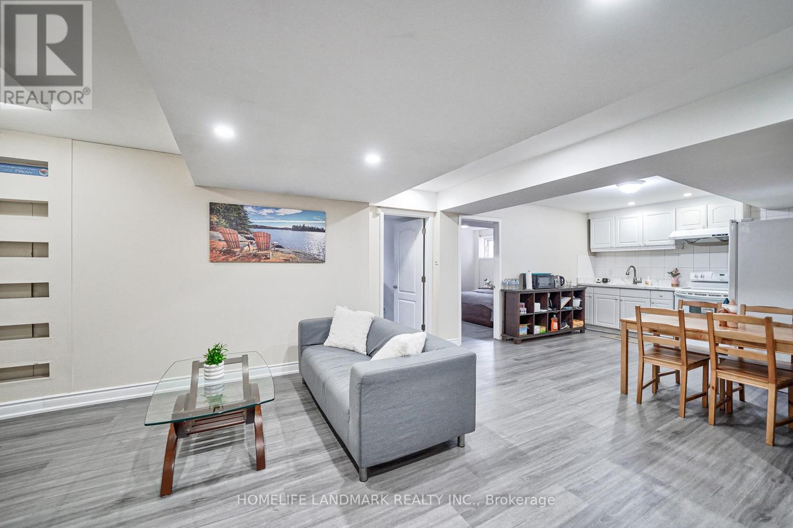 A living room with a grey couch, a glass coffee table, and a wooden dining table.
