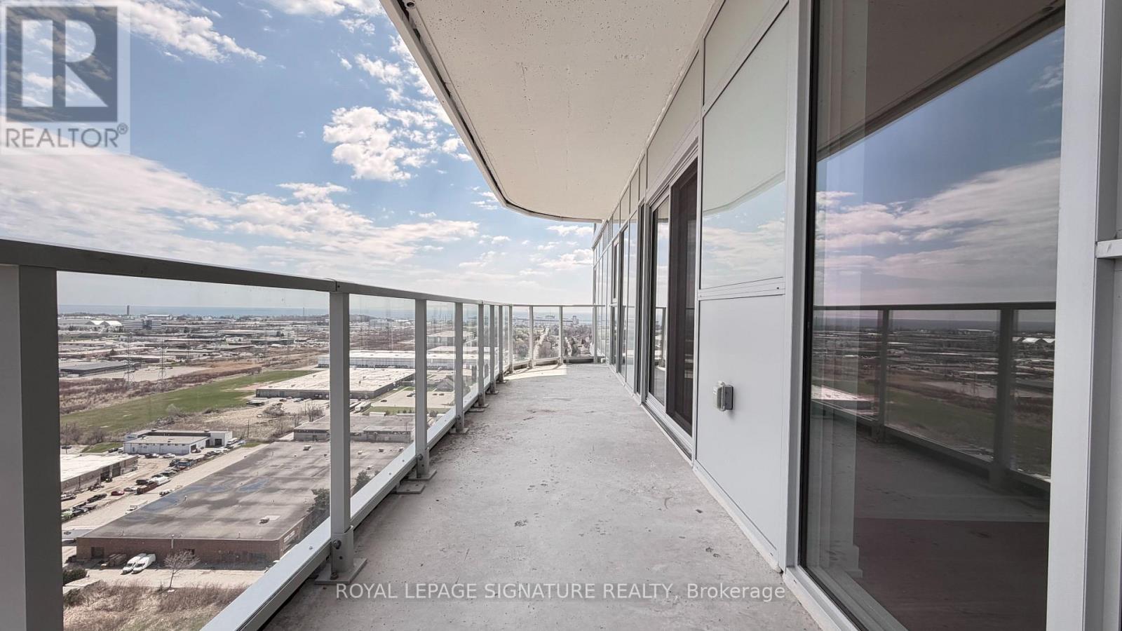 A balcony with a view of a parking lot and buildings.