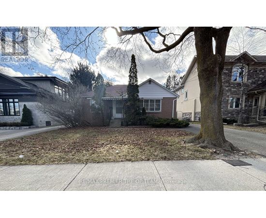 A tree stands in front of a house with a sign that says RE/MAX Premier.