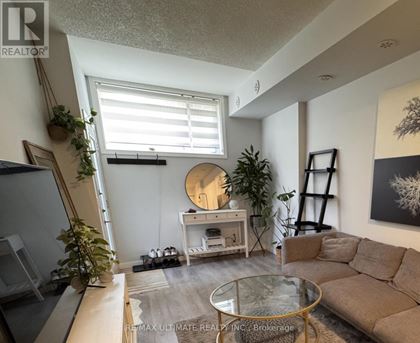 A living room with a couch, coffee table, and plants.