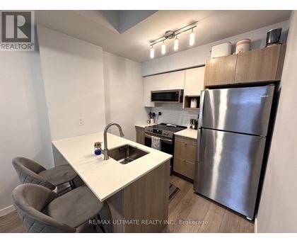 A kitchen with a white counter top and a stainless steel refrigerator.