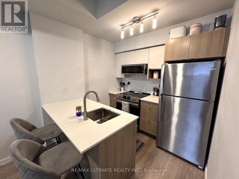 A kitchen with a white counter top and a stainless steel refrigerator.