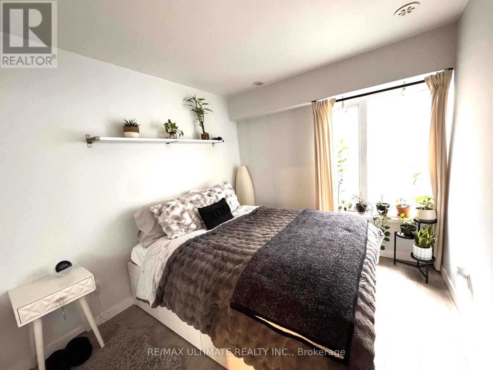 A bedroom with a bed, nightstand, and window.