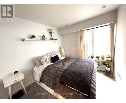 A bedroom with a bed, nightstand, and window.