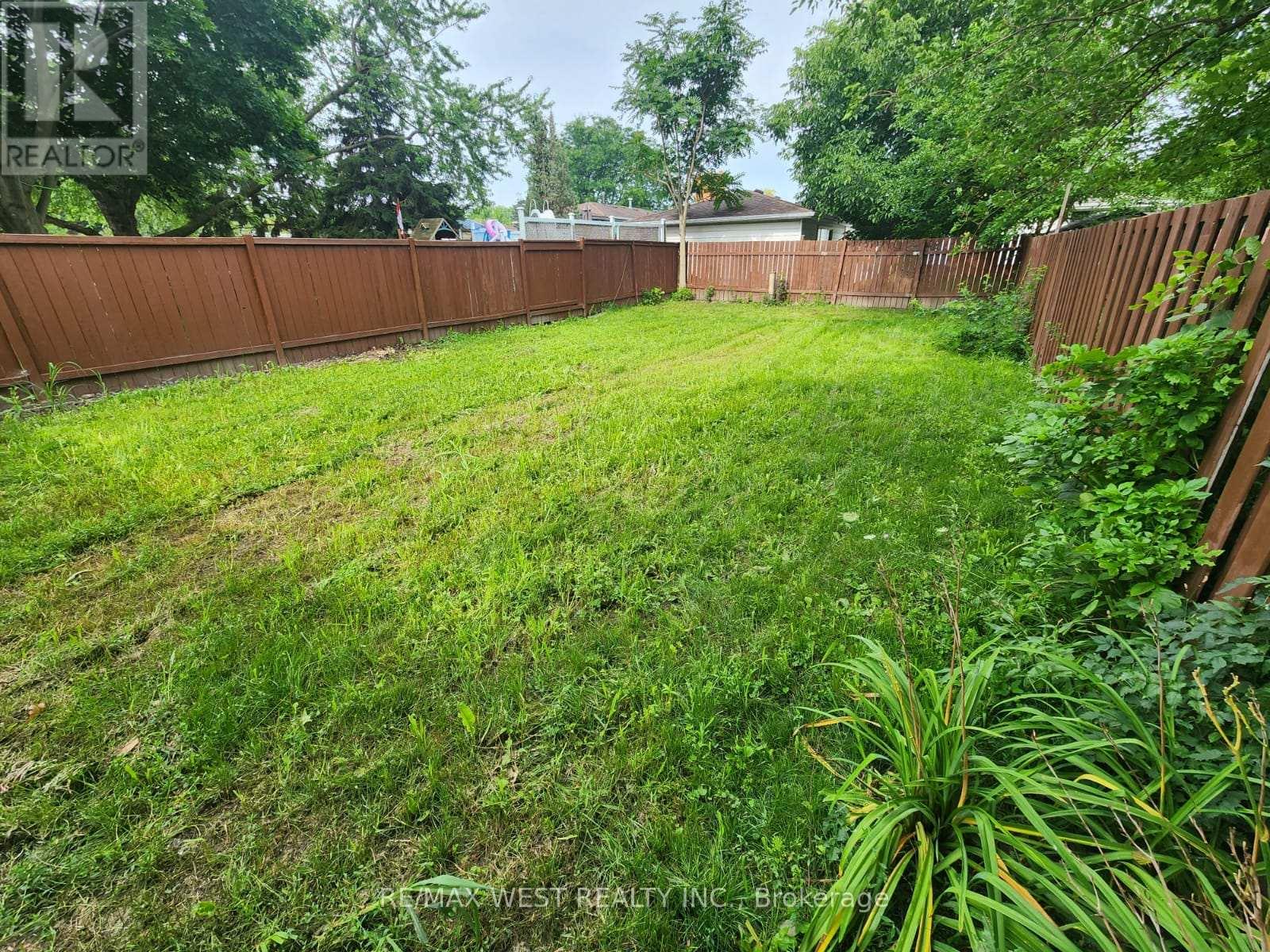 A backyard with a fence and green grass.
