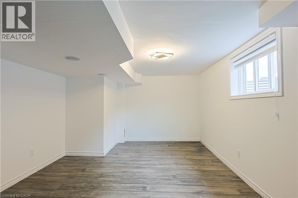 A spacious room with wooden flooring and a window on the right wall.