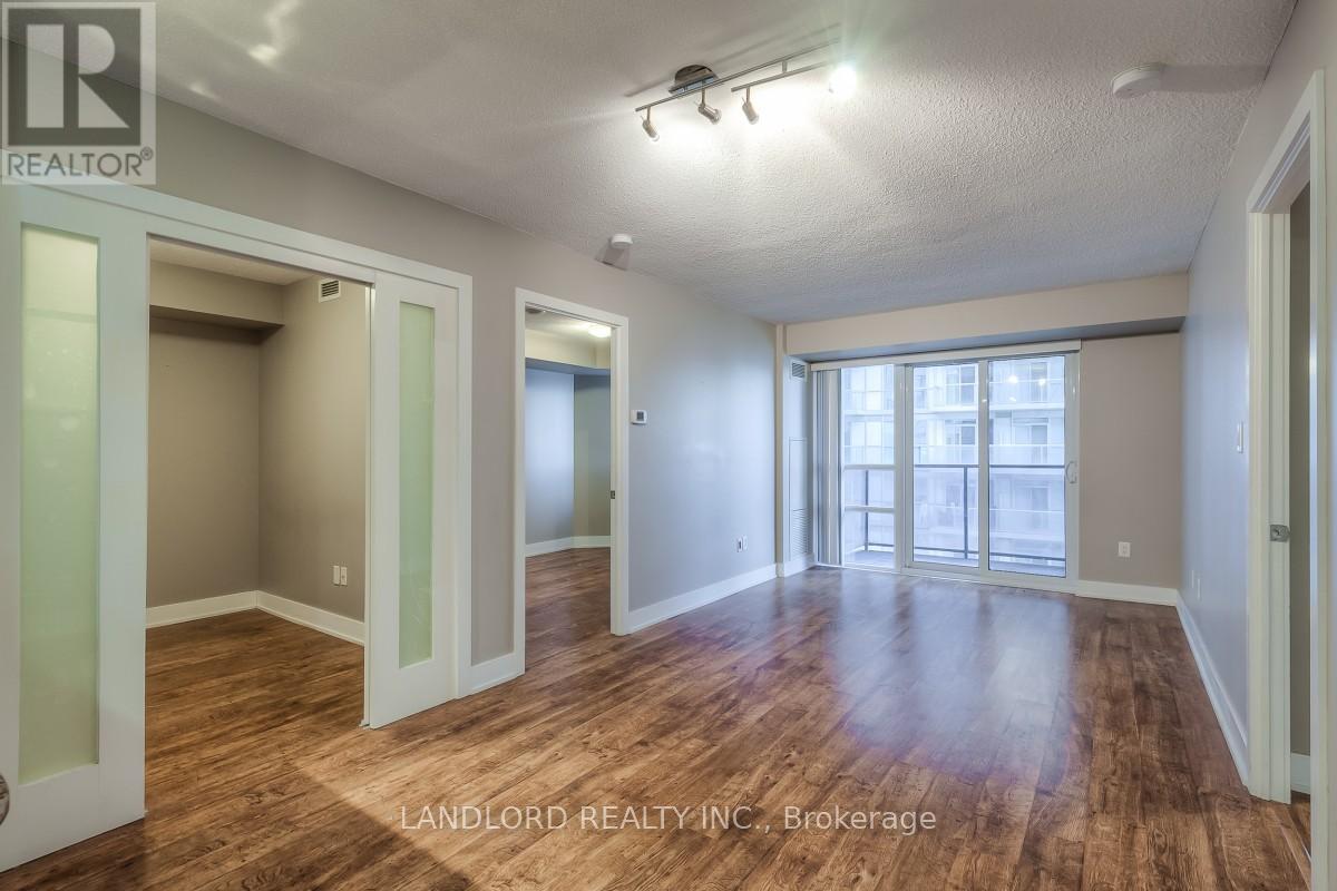 A spacious room with wood flooring and a large window.
