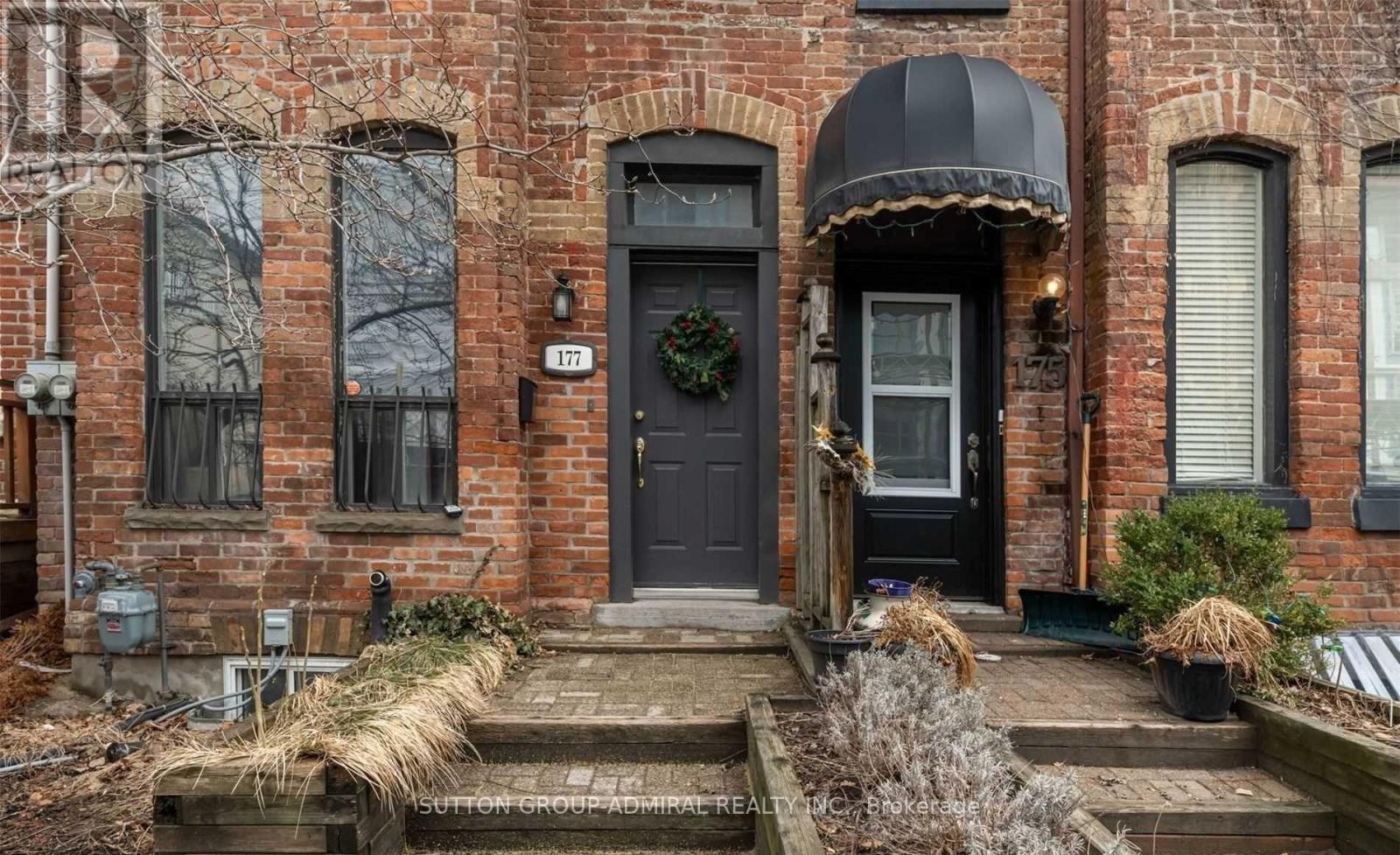 A brick house with a black door and a wreath on it.