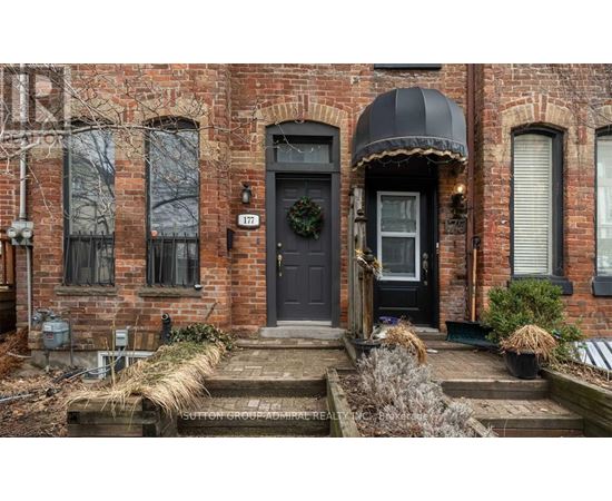 A brick house with a black door and a wreath on it.