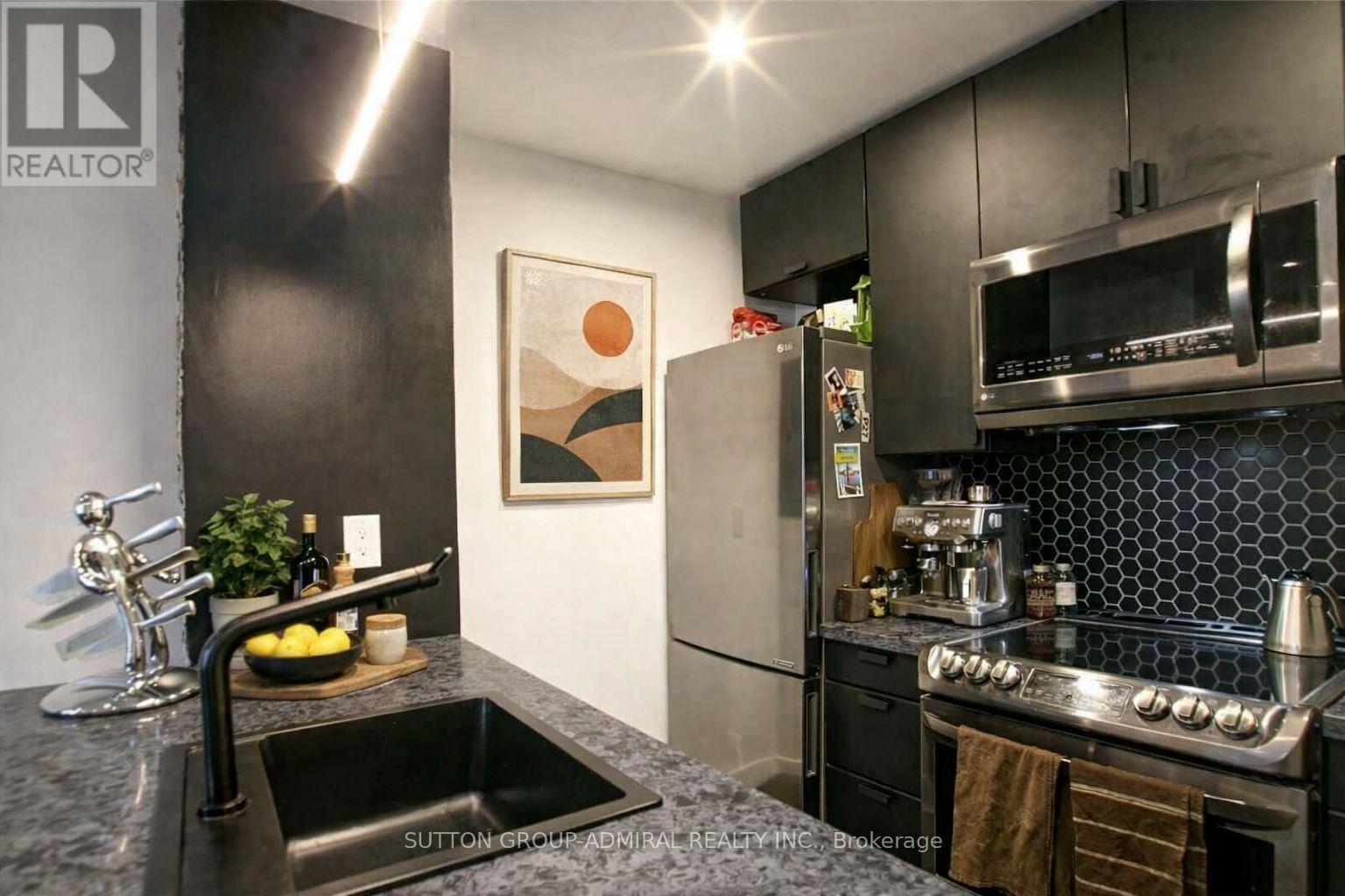 A modern kitchen with a black countertop and stainless steel appliances.