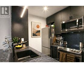 A modern kitchen with a black countertop and stainless steel appliances.