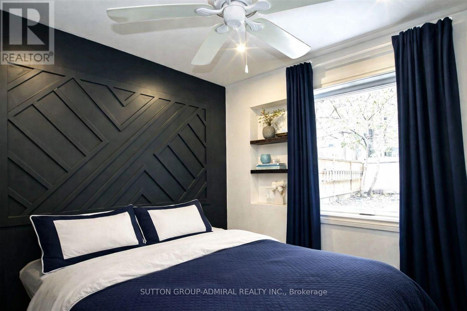 A bedroom with a dark headboard and a window with blue curtains.