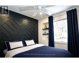 A bedroom with a dark headboard and a window with blue curtains.
