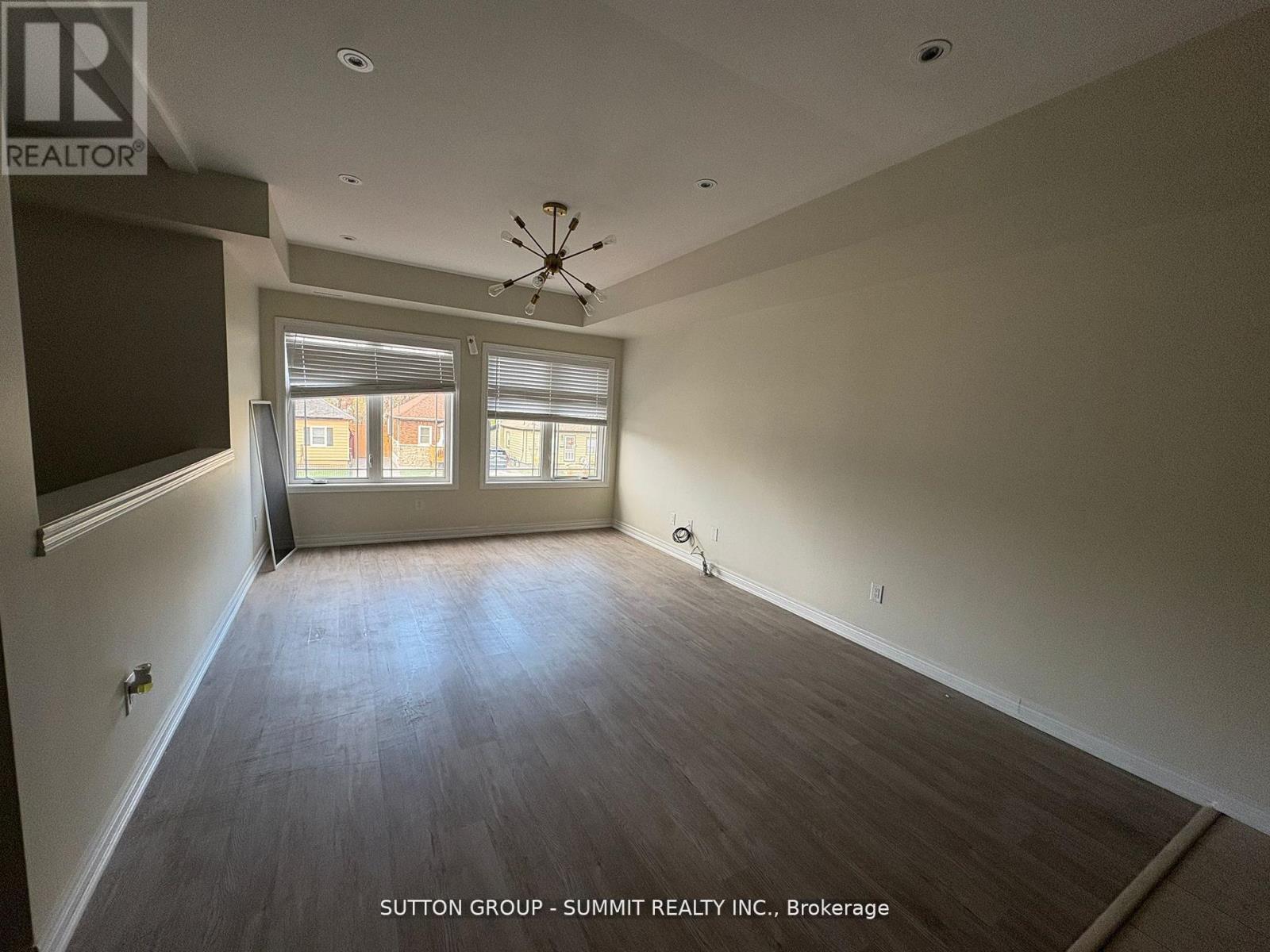 A large empty room with a ceiling fan and a window with blinds.