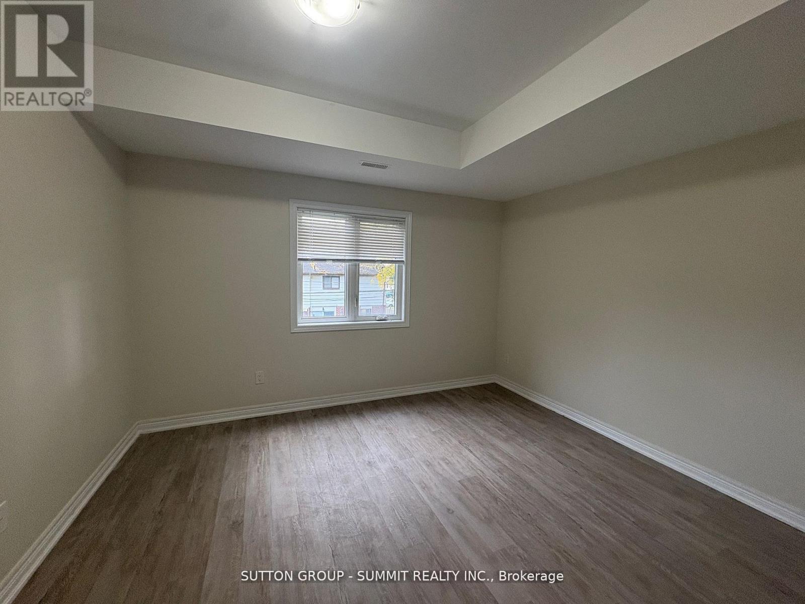A room with wooden flooring and a window with blinds.