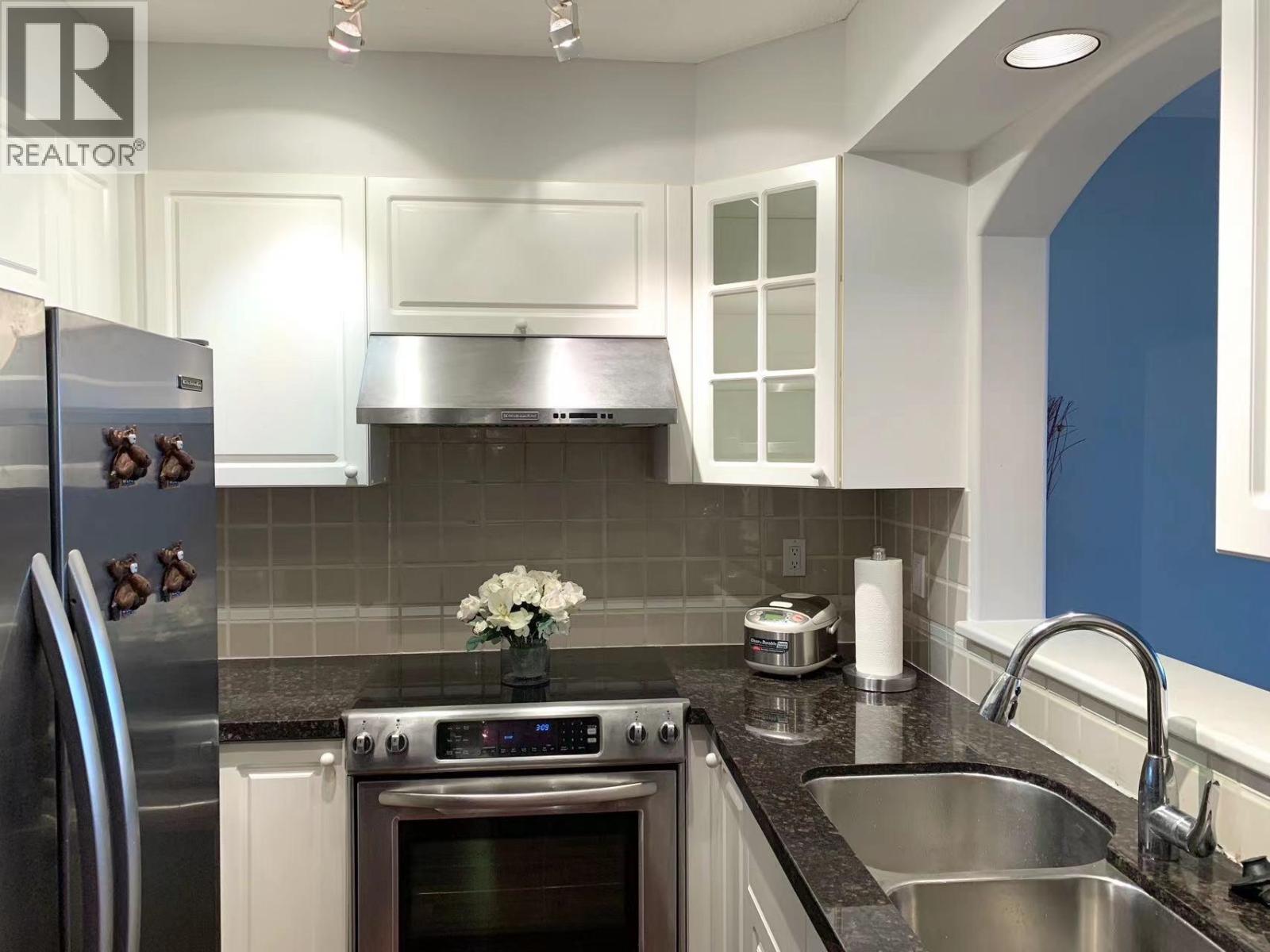 A kitchen with a stainless steel refrigerator and a stove top oven.