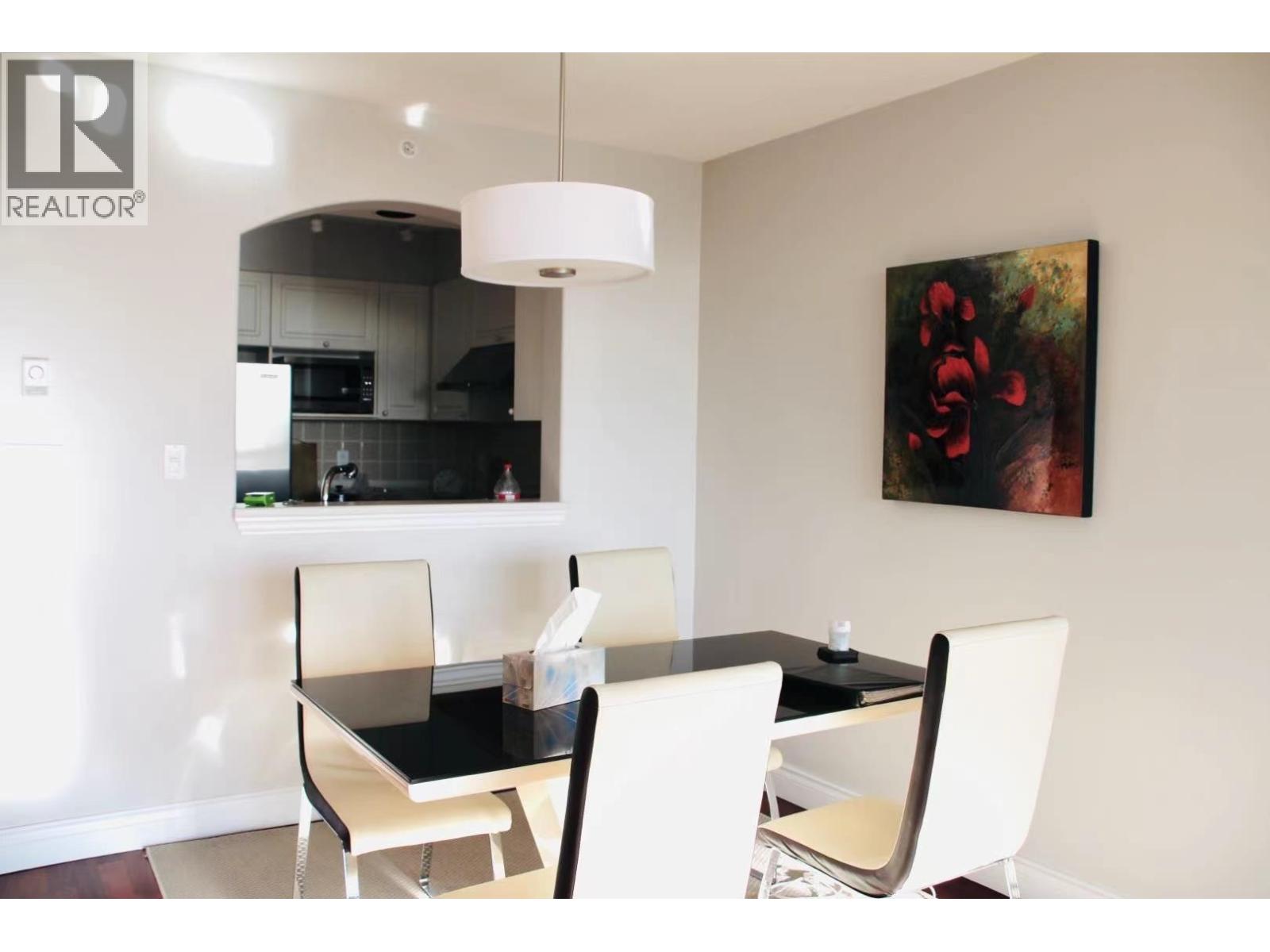 A modern dining room with a black table and white chairs.