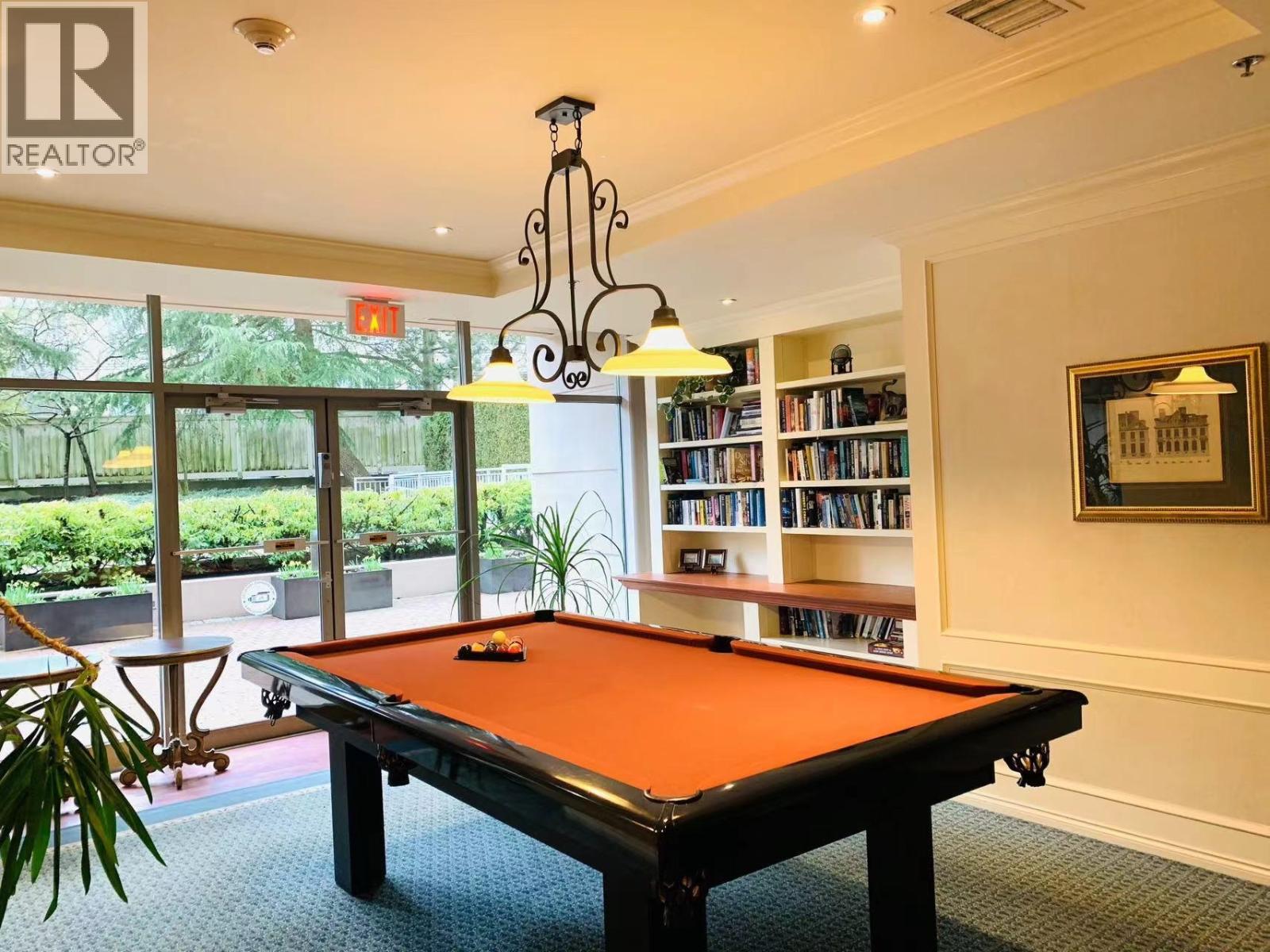 A pool table in a room with a chandelier and bookshelves.