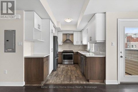 A modern kitchen with white cabinets and wooden floors.