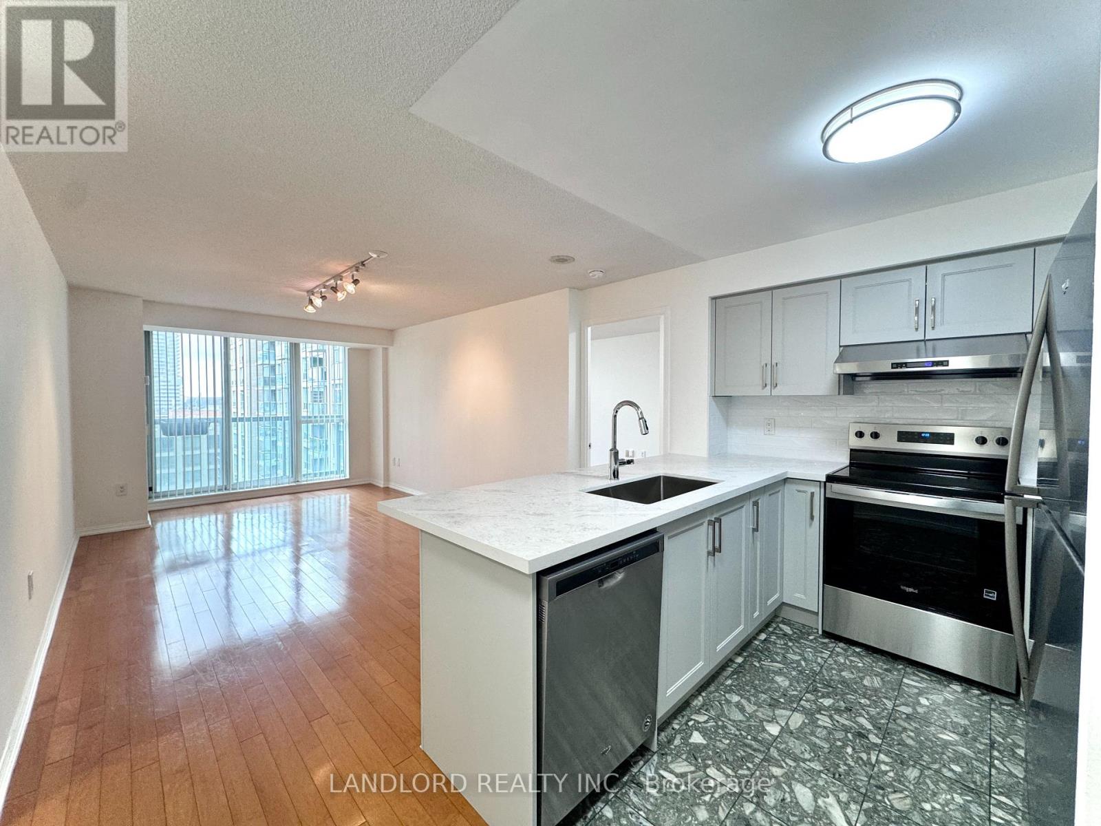 A kitchen with white cabinets and a wooden floor.