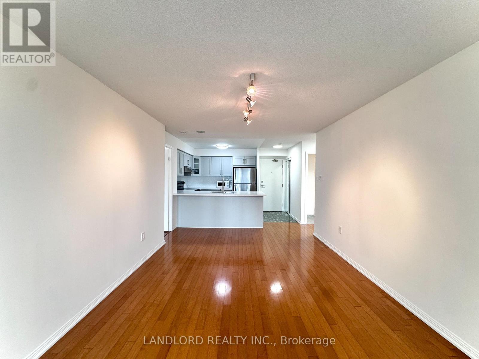 A spacious room with wooden floors and white walls, with a chandelier hanging from the ceiling.