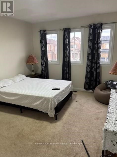 A bedroom with a bed, a window with curtains, and a lamp on a side table.