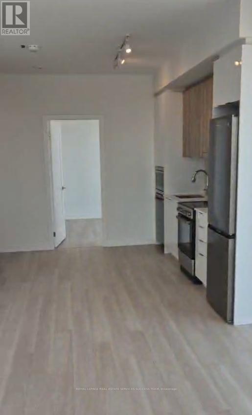 A kitchen with a refrigerator, oven, and sink.