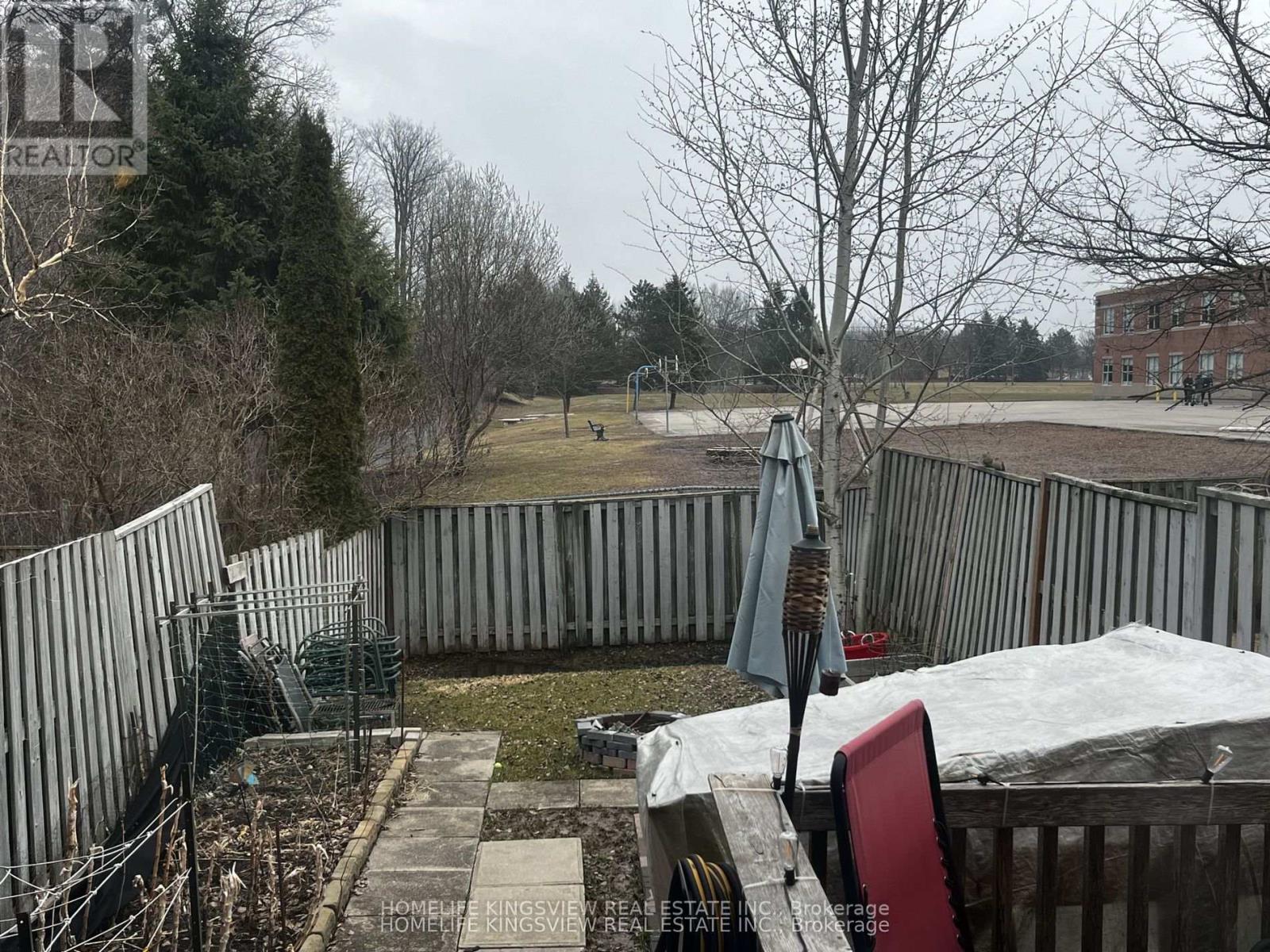 A backyard with a fence, a chair, and a table.