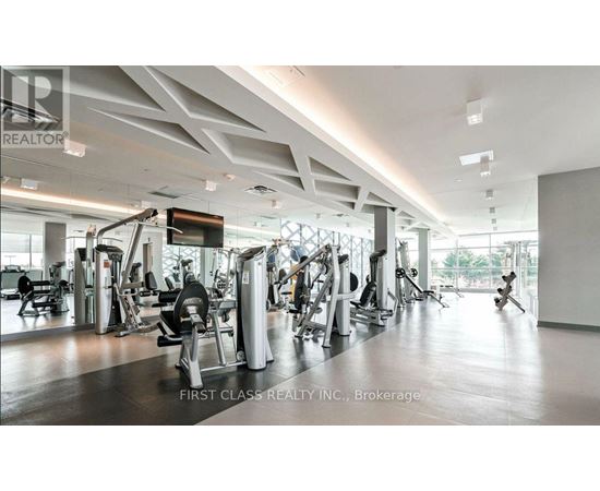 A gym with a variety of equipment is labeled as being owned by First Class Realty Inc.