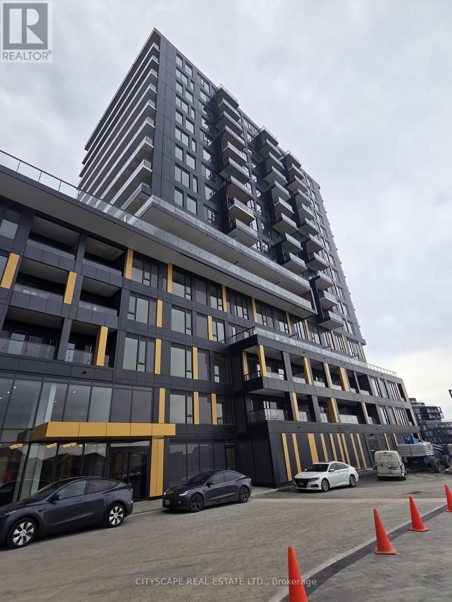A modern multi-story building with a parking lot in front.