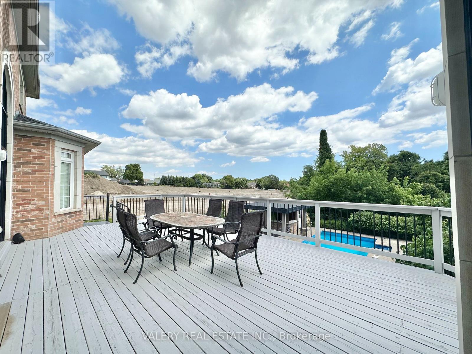A deck with a table and chairs overlooking a pool.