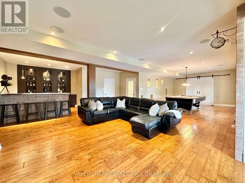 A living room with a black leather sofa and wooden flooring.